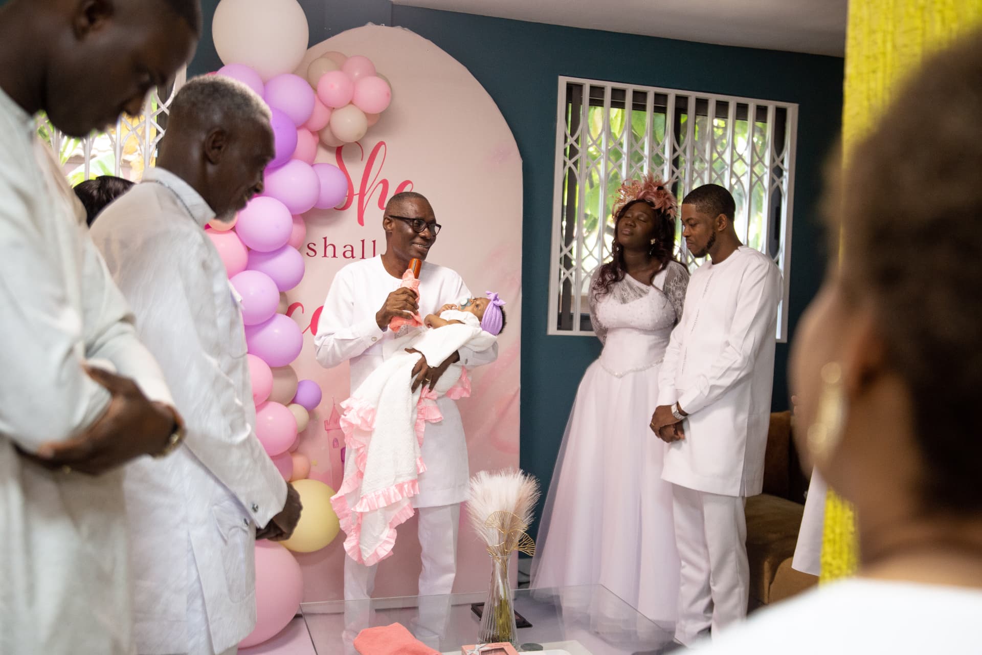 Family gathered at a baby christening under balloons