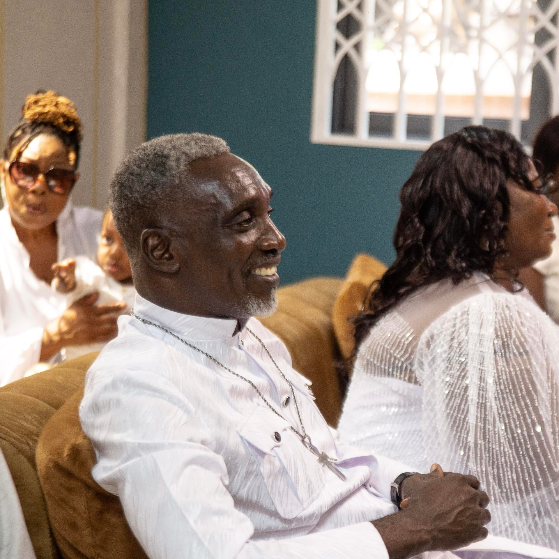Guests in white smiling during a christening celebration