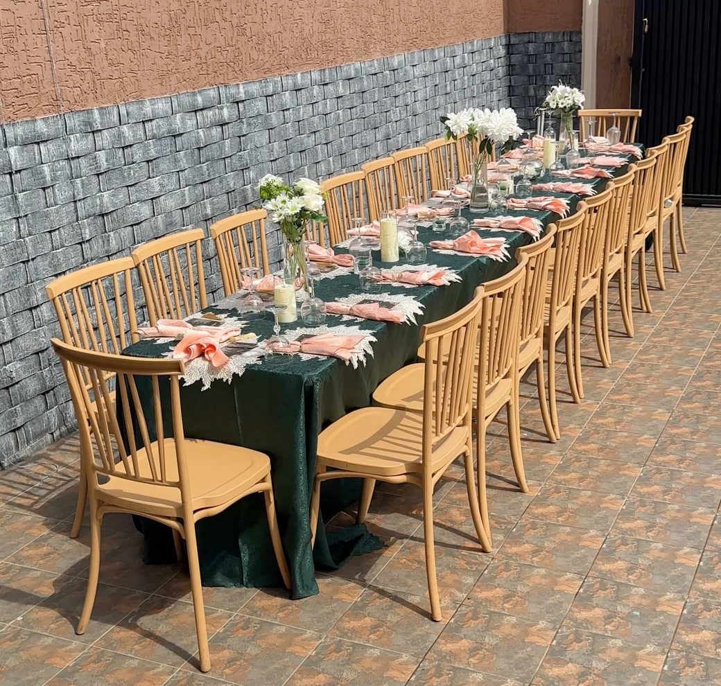 Long dining table dressed in emerald linen with blush napkins and white flowers